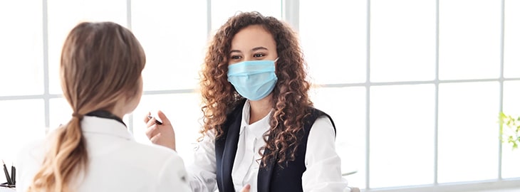 Woman in a medical mask talking with the doctor